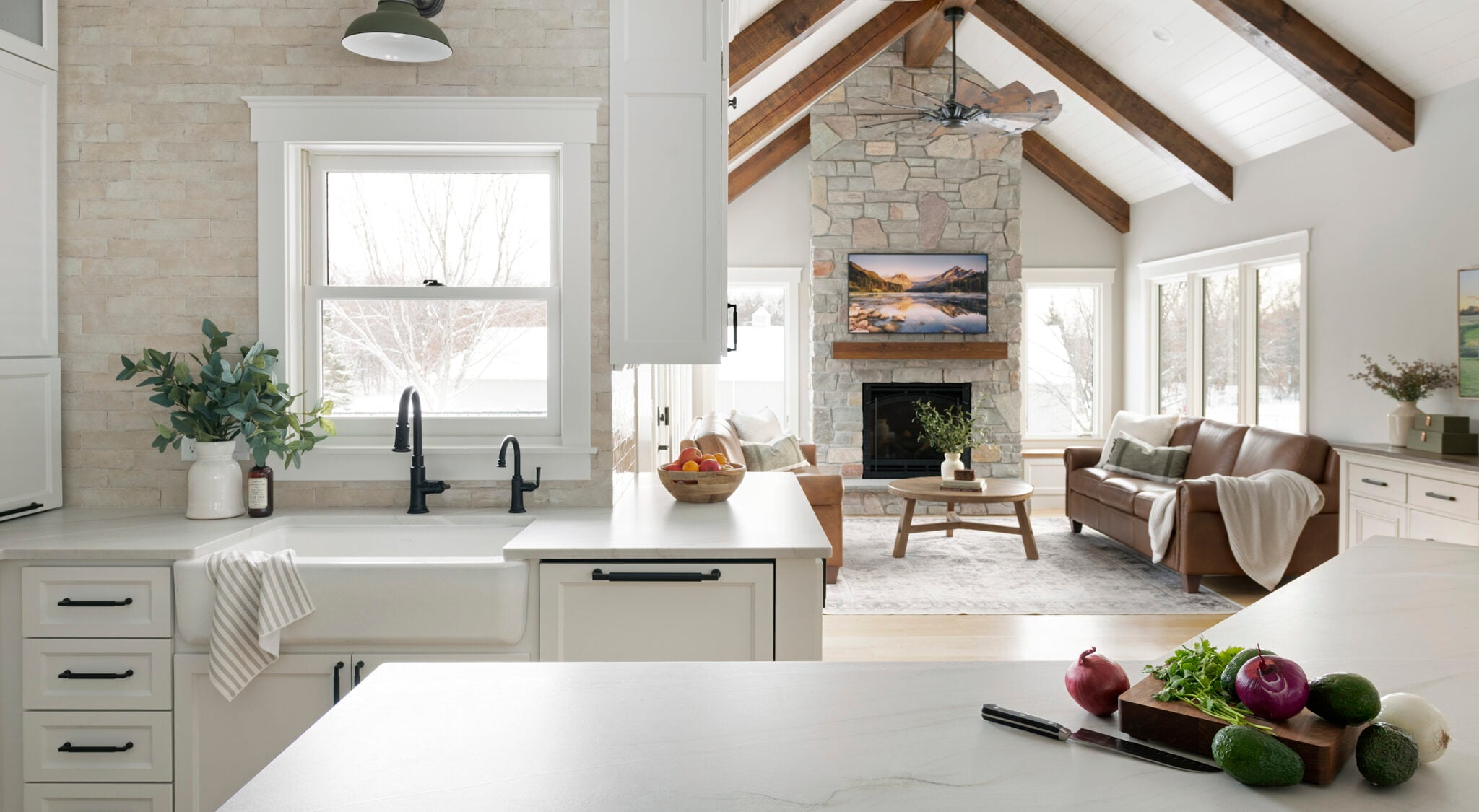 Modern kitchen and living area with stone fireplace.