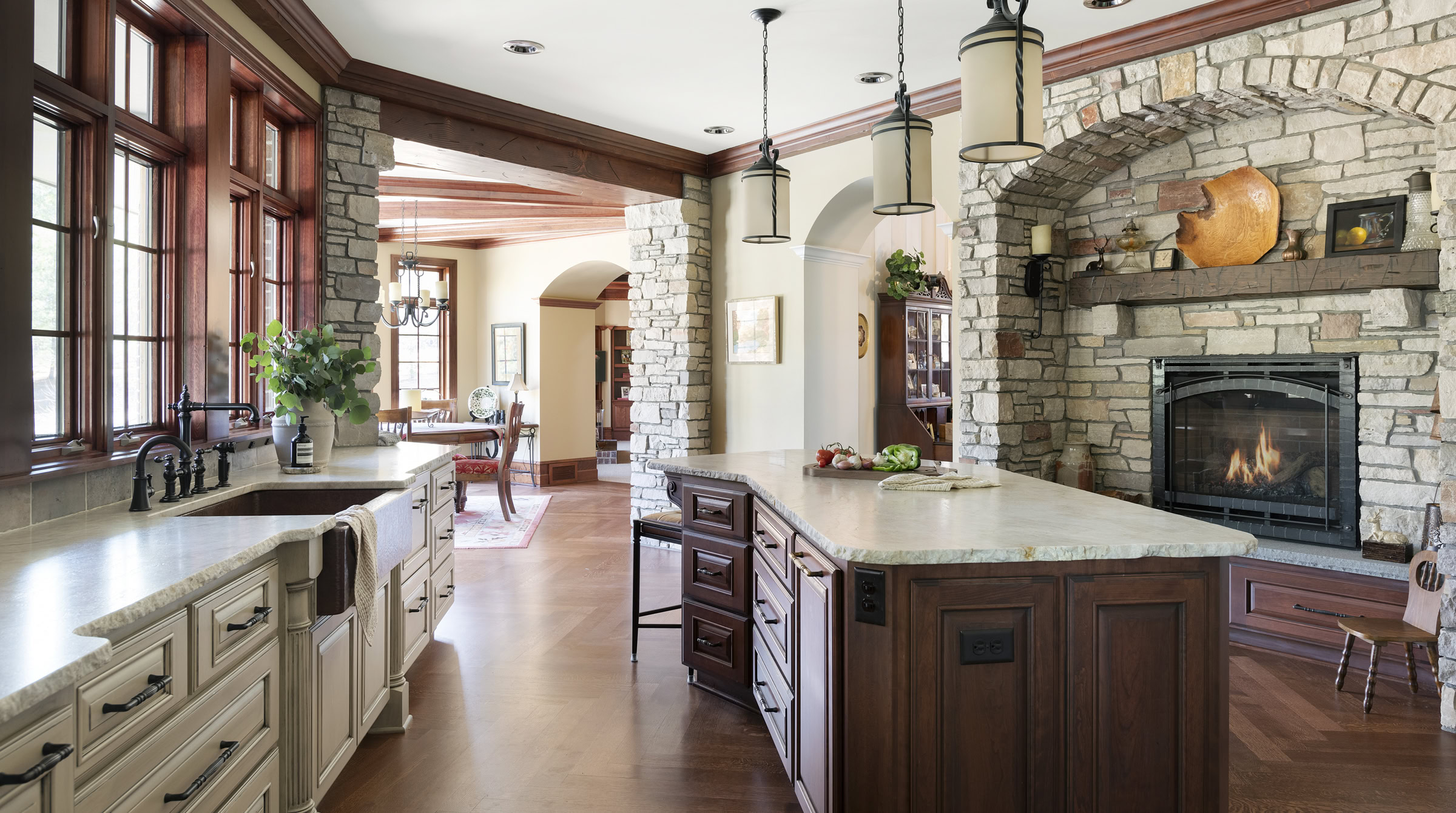 Rustic kitchen with stone fireplace and wooden cabinets.